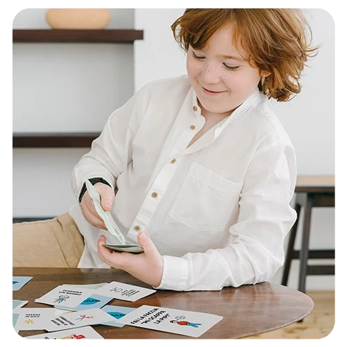 Bambino gioca a carte sorridendo indossando una camicia bianca